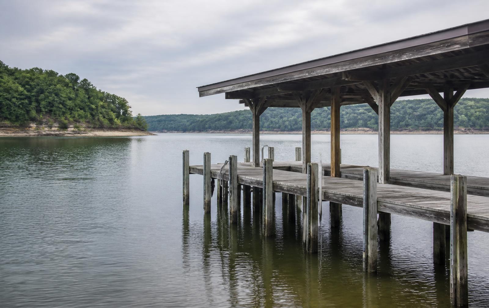Wooden dock and covered boathouse on Lake Guntersville, Alabama, with the waterline band visible on the pilings